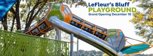 Colorful playground equipment with slides, surrounded by trees, promoting the grand opening of LeFleur's Bluff Playground.