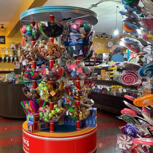 A colorful display of assorted candies and sweets in a shop, featuring various shapes and sizes on a rotating stand.