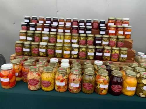 A display of various jars filled with colorful pickled vegetables and preserves, arranged neatly on wooden shelves.