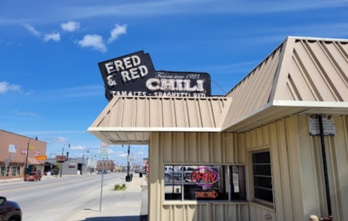 Sign for Fred & Red's restaurant, featuring "Tamales" and "Spaghetti" with a clear blue sky in the background.