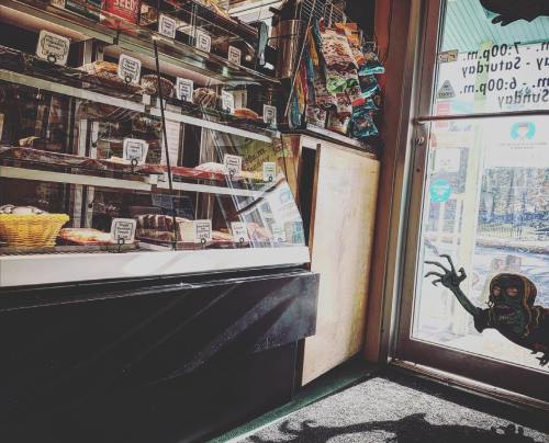 A cozy shop interior with a display case of treats and a door featuring a spooky hand silhouette.