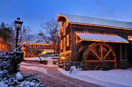 A cozy wooden building adorned with festive lights, surrounded by snow and a serene winter landscape.