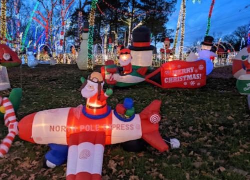 Colorful holiday decorations featuring inflatable characters, including a plane labeled "North Pole Press" and festive lights.