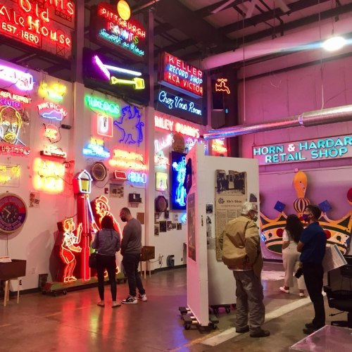A vibrant indoor space filled with colorful neon signs and people exploring the exhibits.