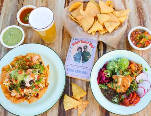 A colorful spread of nachos, salads, and a beer, with a game titled "Sweet Valley High" in the center.