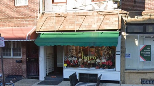 A storefront with a green awning, decorated for the holidays, featuring festive displays in the windows.