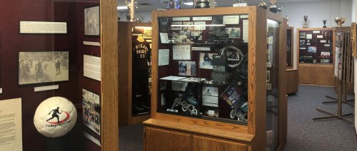 Display of sports memorabilia and trophies in a museum-like setting, featuring glass cases and historical photos.