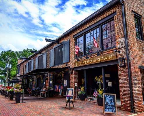 A charming brick building with "Wattle Feed & Grain" sign, featuring American flags and flower planters outside.