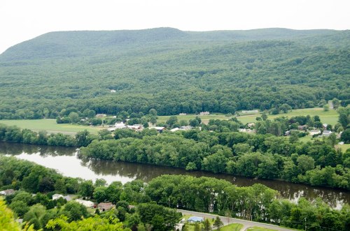 A lush green landscape with a river winding through, surrounded by hills and scattered homes.