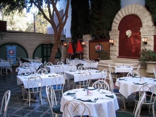 A spacious restaurant with white tablecloths, green chairs, and decorative plants, featuring a cozy, inviting atmosphere.