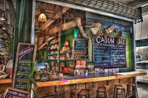 A vibrant café menu featuring Cajun dishes, colorful signage, and a rustic wooden counter in a lively setting.