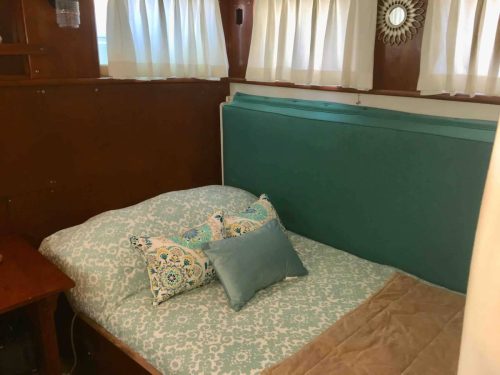 Cozy bedroom with a teal headboard, patterned bedding, and decorative pillows, featuring soft natural light.