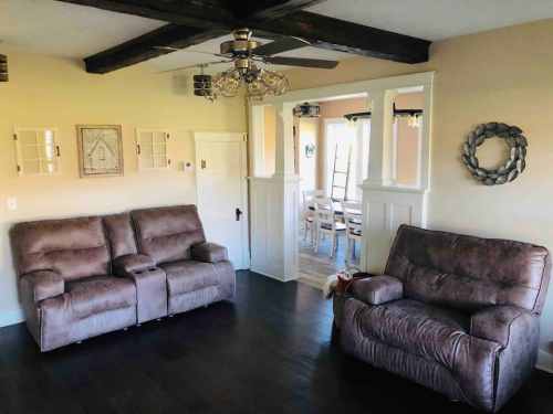 Cozy living room with two brown recliners, wooden beams, and a dining area visible in the background.