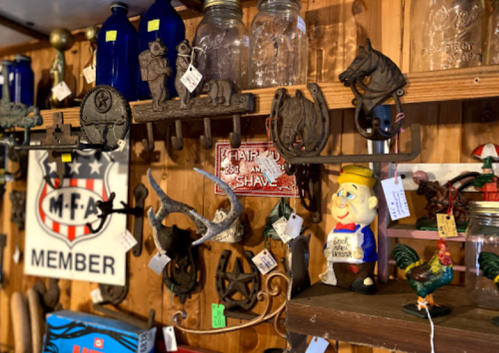 A collection of vintage items, including figurines, tools, and signs, displayed on a wooden wall.