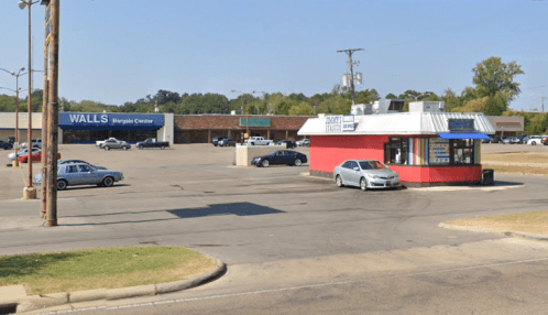A view of a parking lot with a red building and a store labeled "WALLS Bargain Center" in the background.