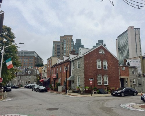 A street view featuring historic buildings alongside modern skyscrapers under a cloudy sky.