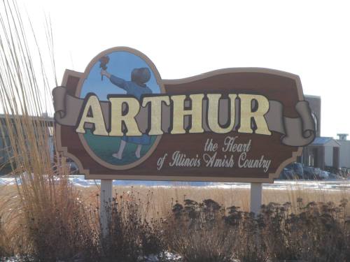 Sign for Arthur, Illinois, featuring a child holding a flower, labeled "the Heart of Illinois Amish Country."