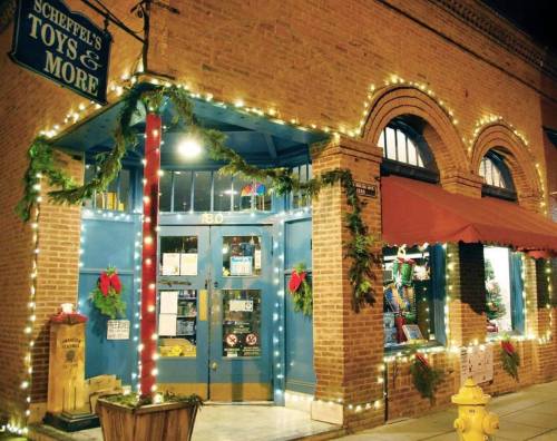 A festive toy store entrance adorned with holiday lights and decorations, creating a warm, inviting atmosphere.