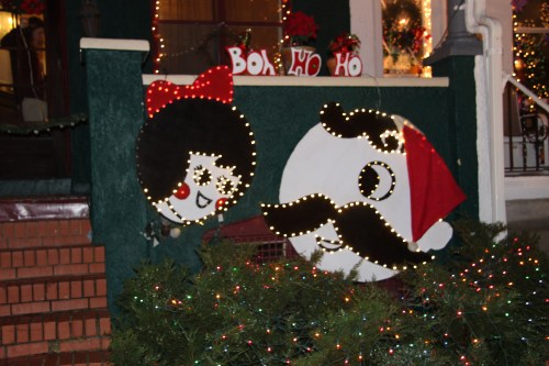 A festive display featuring cartoonish characters with a Santa hat and decorations, surrounded by colorful lights.