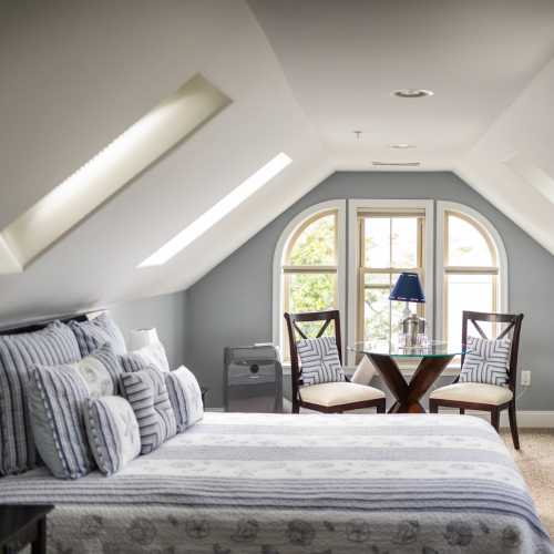 Cozy bedroom with a large bed, decorative pillows, and windows letting in natural light.