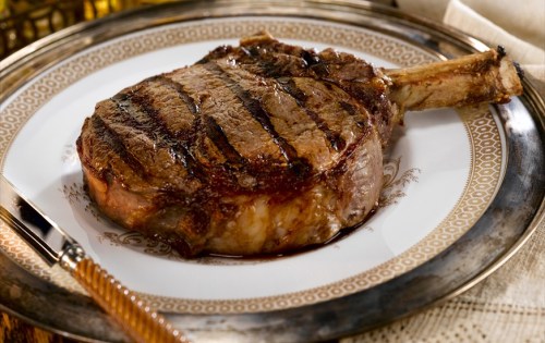 A perfectly grilled ribeye steak on an ornate plate, garnished and ready to serve.