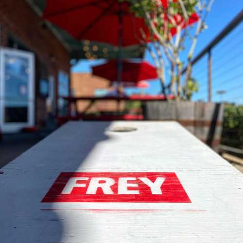 A wooden table with the word "FREY" printed on it, set outdoors with a clear blue sky in the background.