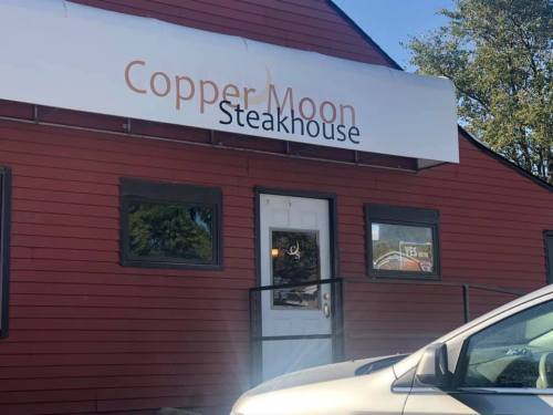 Exterior of Copper Moon Steakhouse, featuring a red building with a sign above the entrance.