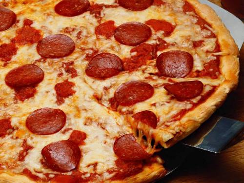 A close-up of a pepperoni pizza with melted cheese and a slice being lifted from the pie.