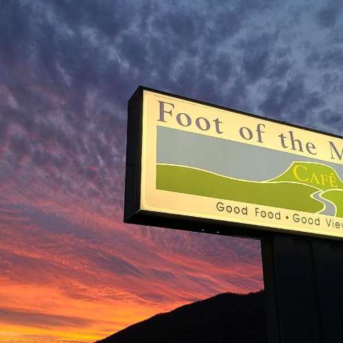 Sign for "Foot of the Cape" café, featuring the tagline "Good Food - Good View" against a colorful sunset backdrop.