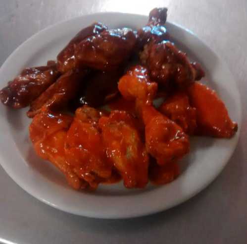 A plate of glazed chicken wings, featuring a mix of crispy and saucy varieties in vibrant orange and brown hues.