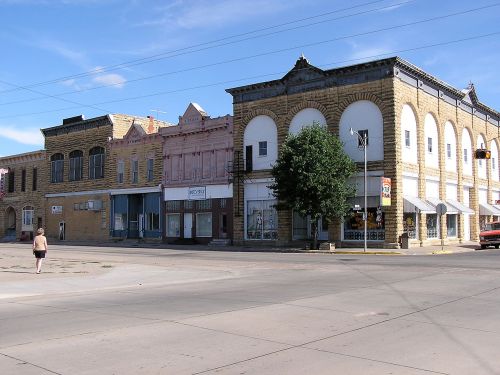 A street view of historic buildings with a person walking, featuring a mix of architectural styles and storefronts.