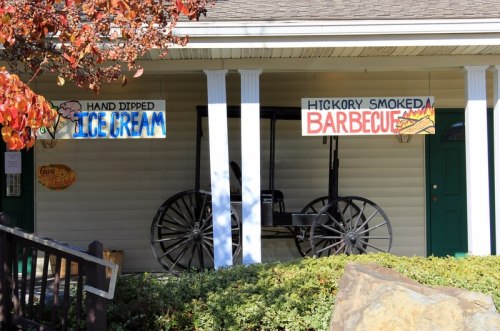 A building with signs for "Hand Dipped Ice Cream" and "Hickory Smoked Barbecue," featuring a vintage wagon in front.