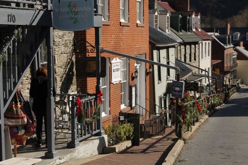 A quaint street lined with historic buildings, decorated for the holidays, featuring greenery and festive accents.