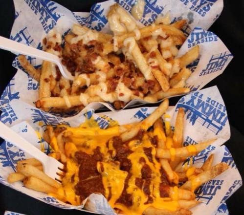 Two servings of loaded fries: one topped with cheese and bacon, the other with chili and melted cheese, served in paper baskets.