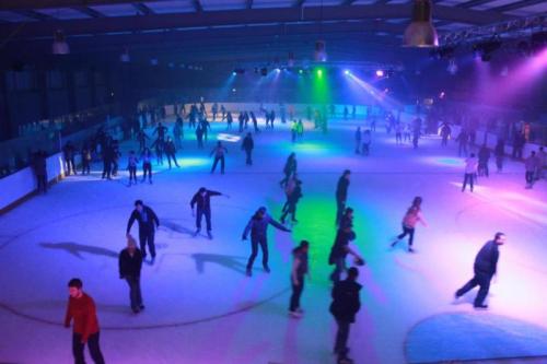 A vibrant ice skating rink filled with people skating under colorful lights.