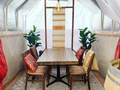 Cozy indoor space with a wooden table, four chairs, plants, and decorative elements in a bright, airy setting.