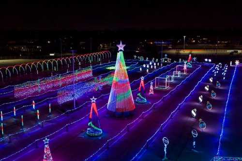 A vibrant display of colorful Christmas lights, featuring a large tree and various festive decorations in a nighttime setting.