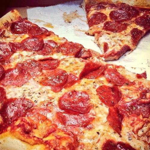 A close-up of a pizza with melted cheese and pepperoni slices, with a few pieces missing.