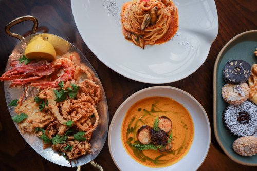 A spread of seafood dishes, including fried crab, pasta, and a creamy seafood bowl, alongside an assortment of desserts.