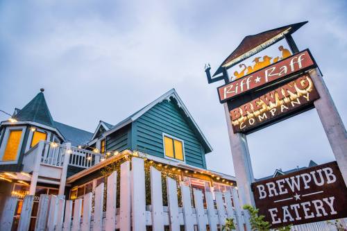 A charming brewpub with a sign for Riff Raff Brewing Company, featuring a cozy building and outdoor seating.