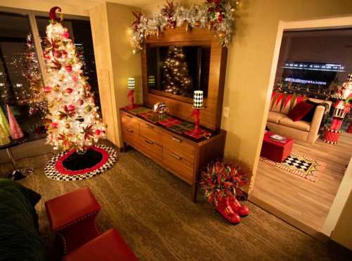 Cozy holiday-themed room with a decorated Christmas tree, festive decor, and a view of city lights through the window.