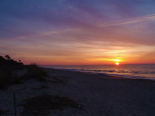 A serene beach at sunset, with vibrant colors in the sky and gentle waves lapping at the shore.