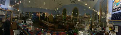 A cozy café interior with string lights, wooden tables, and a colorful counter, creating a warm, inviting atmosphere.