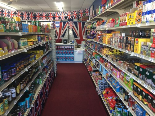 A grocery store aisle lined with various products, decorated with British flags and colors.