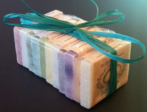 A stack of colorful, wrapped soaps tied with a green ribbon on a dark background.