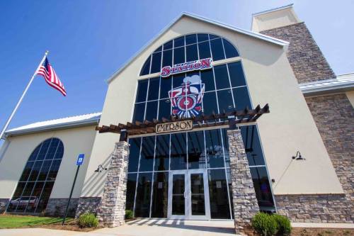 Exterior view of a modern building with large windows, stone accents, and an American flag in front.