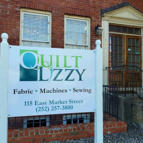 Sign for Quilt Lizzy, a fabric and sewing shop located at 115 East Market Street, with contact number displayed.