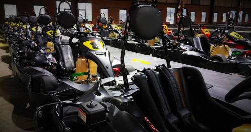 A row of go-karts lined up in an indoor racing facility, ready for use.