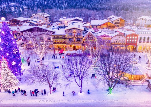 A snowy village scene with festive lights, a large Christmas tree, and people enjoying the winter atmosphere.