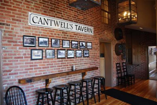Interior of Cantwell's Tavern featuring a brick wall, black-and-white photos, and wooden seating.